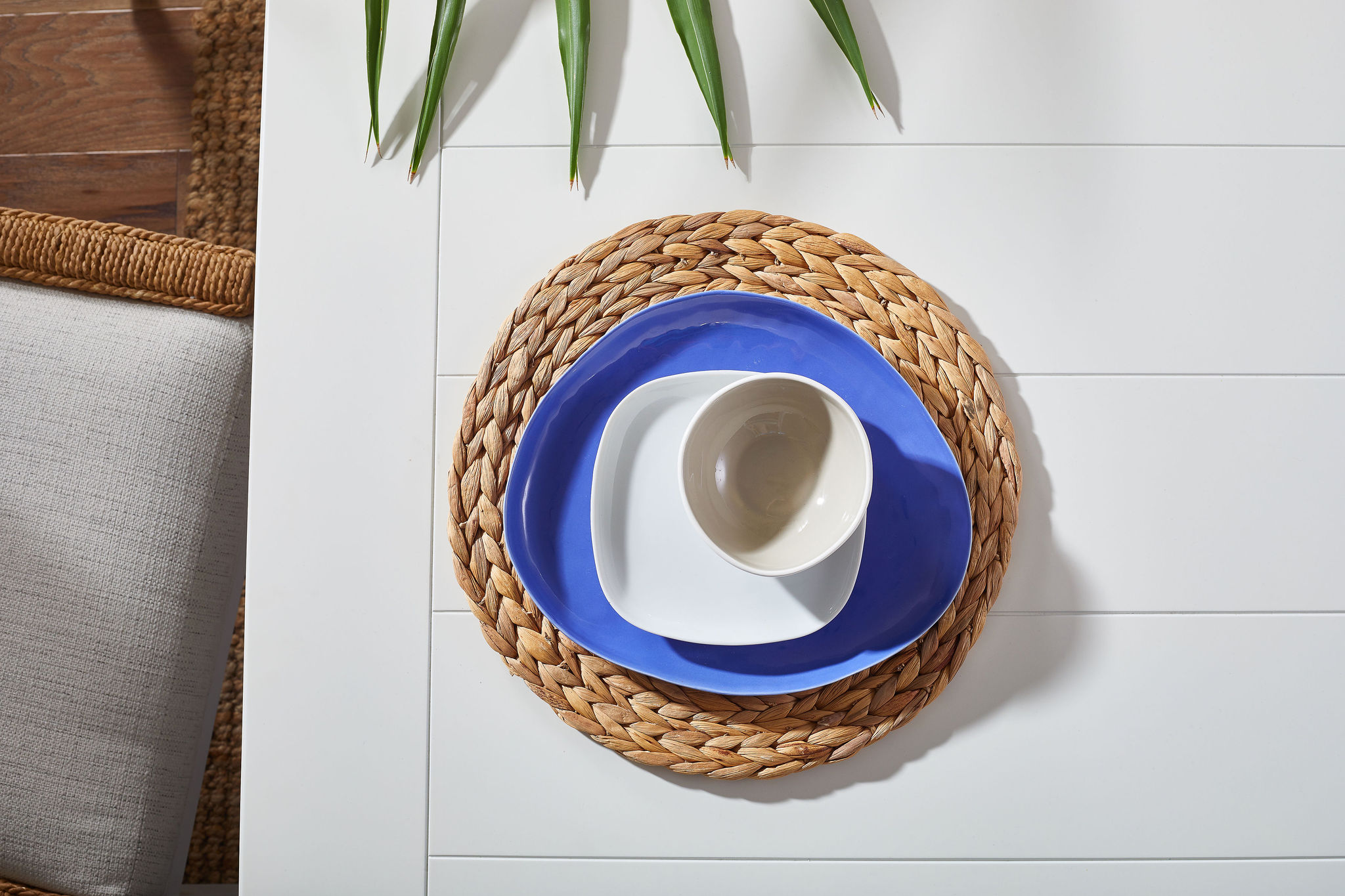 Woven placemat with a blue plate, white side plate and white bowl on top