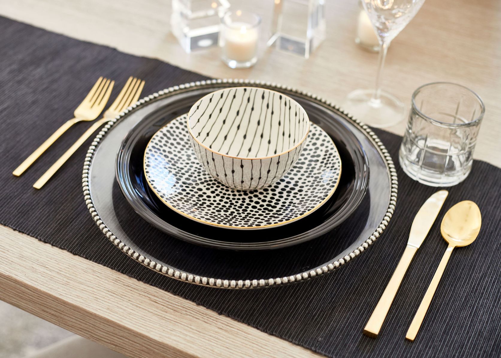 table with black tablecloth, plate, gold flatware, and patterned bowls